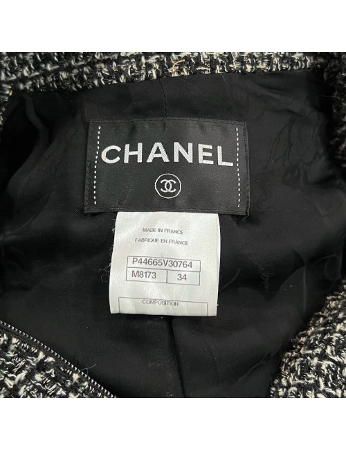 Veste T34 CHANEL en tweed noir et blanc avec fil doré. Fermeture avec zip et deux poches passepoilées sur le devant