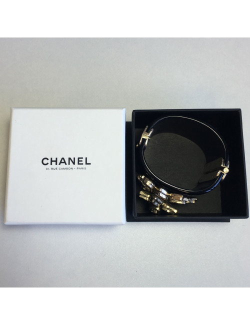 Manchette CHANEL en résine noire et fleur en métal doré et résine transparente